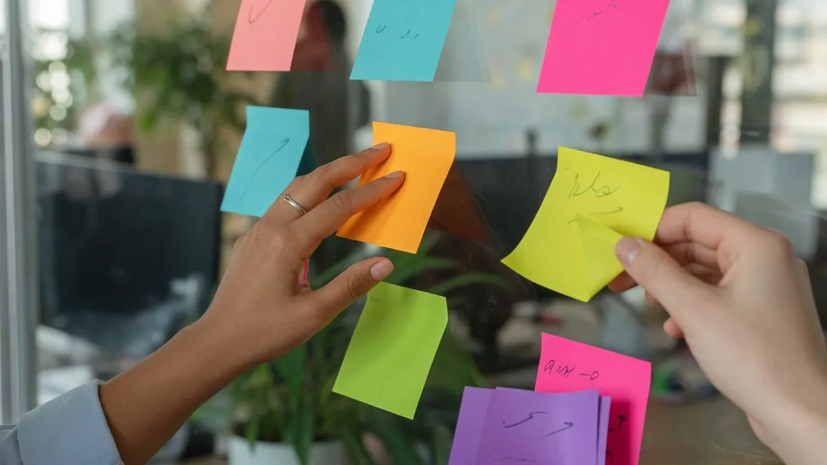 Mains organisant des notes de priorités sur un tableau blanc